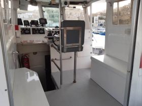 The interior of a boat's helm area showcases the control console and seating, providing a glimpse into the operational space for navigating the waters.