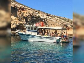 A lively group enjoys a day on the water aboard the Ta Miema Boat Service, perfect for swimming and exploring beautiful coastal scenery.