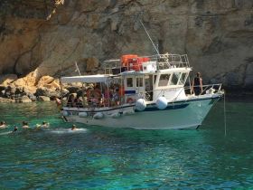 A lively group enjoys snorkeling in crystal-clear waters near a boat, creating a perfect summer adventure in a stunning coastal setting.