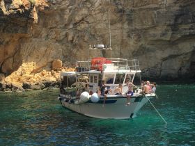 A lively group enjoys a day on the water aboard a boat, relaxing and taking in the stunning coastal scenery.