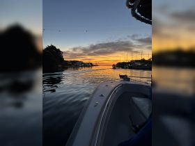 A serene sunset view from the deck of a boat, showcasing calm waters and a picturesque marina backdrop — perfect for evening cruises.