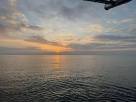A serene sunset view over calm waters, captured from a boat, creating a picturesque backdrop perfect for evening cruises.