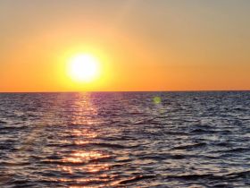 A breathtaking sunset over the ocean, casting golden reflections on the water — a perfect backdrop for romantic evenings or serene boat trips.