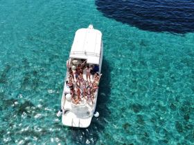 A lively group enjoys a fun day on a boat in crystal-clear waters, celebrating with drinks and laughter — perfect for summer outings and memorable gatherings.