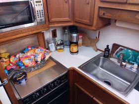 A cozy boat kitchen featuring a variety of snacks, a microwave, and essential appliances, perfect for preparing meals while on the water.