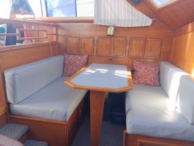 Cozy interior seating area of a boat featuring comfortable cushions and a dining table, perfect for relaxing or enjoying meals while on the water.