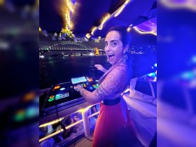 A lively DJ performs on a boat at night, with the iconic Sydney Harbour Bridge illuminated in the background — perfect for unforgettable party experiences on the water.