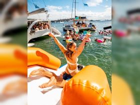 A lively scene of friends enjoying a sunny day on the water, celebrating with fun activities on a floating mat — perfect for summer parties and group outings.