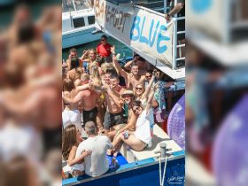 A lively group celebrates aboard the Barefoot Blue, enjoying drinks and sunshine — the perfect atmosphere for a fun day on the water.