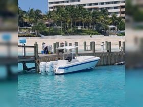 A sleek speedboat is docked at a vibrant marina, surrounded by clear turquoise waters and lush palm trees, perfect for a day of adventure on the water.