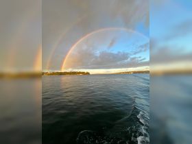A stunning view of a double rainbow arching over calm waters, creating a picturesque scene perfect for nature lovers and boating enthusiasts.