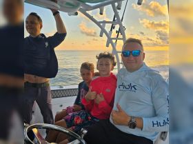A joyful family enjoys a sunset fishing trip on a boat, with kids giving thumbs up — a perfect moment for creating lasting memories on the water.