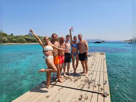 A cheerful group poses on a dock, enjoying a sunny day by the turquoise waters — perfect for summer adventures and memorable gatherings.
