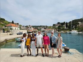 A cheerful group of friends poses together at a picturesque harbor, capturing the essence of their boating adventure in a charming coastal town.