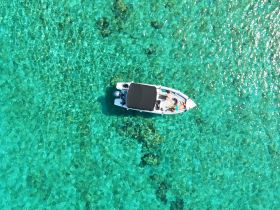 A stunning aerial view of a boat cruising through crystal-clear turquoise waters, showcasing a perfect day on the water.