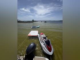 A jet ski and paddleboards are anchored in calm waters, showcasing the perfect setup for a day of fun on the water.