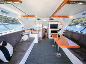A spacious and stylish interior of a boat featuring comfortable seating and a well-equipped helm area, perfect for relaxing or navigating the waters.