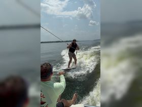 A thrilling moment captured as a young man wakeboards behind a boat, showcasing the excitement of water sports and summer fun.