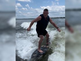 A man enjoys wake surfing on a beautiful day, showcasing the thrill of water sports and adventure on the water.