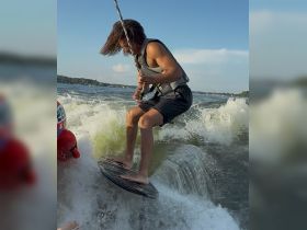 A thrilling moment captured as a young man enjoys wakeboarding on a sunny day, showcasing the excitement of summer water sports.
