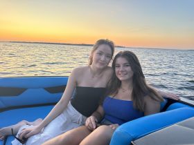 Two young women enjoy a beautiful sunset on a boat, capturing a perfect moment of friendship and relaxation on the water.