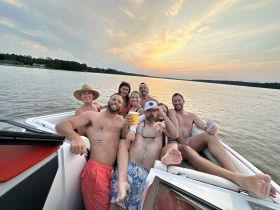 A lively group of friends enjoys a sunset boat ride, celebrating with drinks and laughter on the water — the perfect backdrop for unforgettable summer memories.