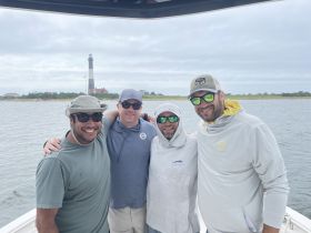A group of friends poses for a photo on a boat with a lighthouse in the background, capturing a memorable moment on the water.