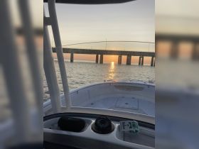 A serene view from the helm of a boat at sunset, showcasing the interior space and the beautiful reflection on the water.