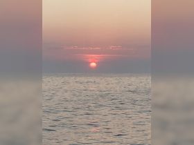 A stunning sunset over calm waters, creating a picturesque scene perfect for romantic evenings or peaceful boat rides.