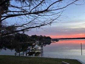 A serene sunset view featuring a boat docked at the pier, reflecting beautifully on the calm waters — a perfect scene for tranquil evenings by the water.