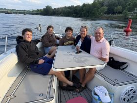 A joyful family enjoys quality time on a boat, sharing drinks and laughter — a perfect setting for summer outings on the water.