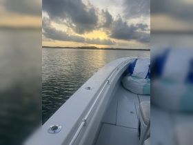 A serene view from the front of a boat at sunset, showcasing the tranquil waters and a hint of the shoreline in the background — perfect for peaceful evening cruises.