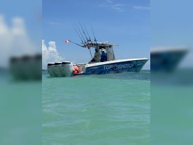 A fishing charter boat named 'Top Notch' is seen on the water with anglers preparing for a day of fishing — a perfect adventure for fishing enthusiasts.