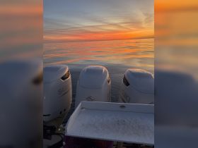 A serene view of boat engines against a stunning sunset, showcasing the calm waters and vibrant colors — perfect for evening cruises.