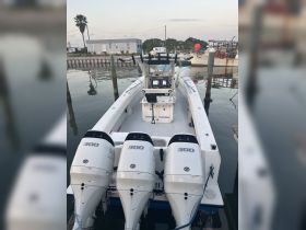 A detailed view of the helm and console area of a boat, showcasing the three powerful 300 HP engines and the sleek design, perfect for fishing or cruising adventures.