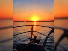A stunning sunset view from the bow of a boat, showcasing the tranquil waters and vibrant colors of the horizon — perfect for romantic evening cruises.