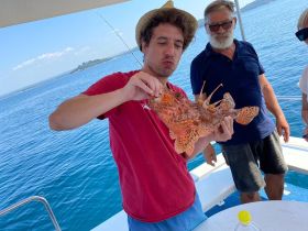 A group of friends celebrates a successful fishing trip, showcasing their catch on a boat — a perfect moment for seafood lovers and adventure seekers.