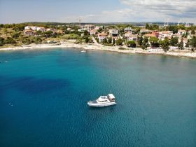Aerial view of a boat anchored in crystal-clear waters, surrounded by a picturesque coastal landscape — perfect for exploring the beautiful shoreline.