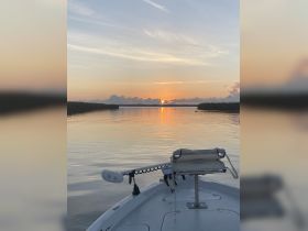 A serene view from the front of a boat at sunset, showcasing calm waters and a picturesque sky — perfect for tranquil evening cruises.