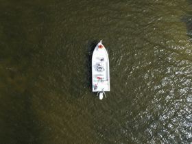 Aerial view of a boat navigating through calm waters, showcasing its sleek design and structure — perfect for fishing or leisure outings.