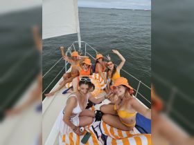 A lively group of friends enjoys a fun day on the boat, celebrating with vibrant outfits and smiles, perfect for summer adventures on the water.
