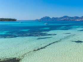 A stunning view of turquoise waters and a distant island, showcasing the beauty of a serene coastal landscape — perfect for exploring by boat.