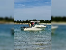 A fishing charter boat is anchored in clear waters, with guests enjoying their time on board — a perfect setting for a day of adventure on the water.
