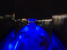 A vibrant interior shot of a boat at night, featuring illuminated seating and a sleek helm, perfect for evening cruises and adventures on the water.