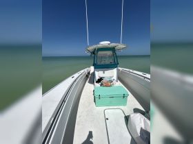A clean and spacious interior view of a boat's helm area, featuring a cooler and seating, perfect for day trips on the water.