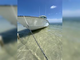 A striking view of a boat anchored in shallow waters, showcasing its sleek design against a clear blue sky — perfect for a day out on the water.