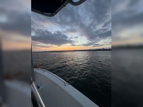 A serene sunset view from a boat, with a foot visible on the edge, capturing the tranquil beauty of the water and sky — perfect for evening cruises.
