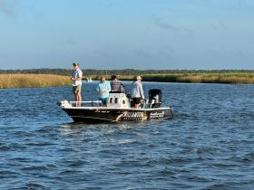 A group of friends enjoys a fishing trip on a boat, surrounded by scenic waterways and lush greenery — perfect for outdoor adventures.