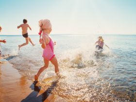 A joyful scene of children splashing in the water at the beach, capturing the essence of summer fun and carefree moments by the shore.