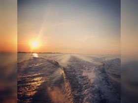 A stunning sunset over the water, showcasing beautiful reflections and a serene coastline — perfect for capturing the essence of a peaceful evening on the water.